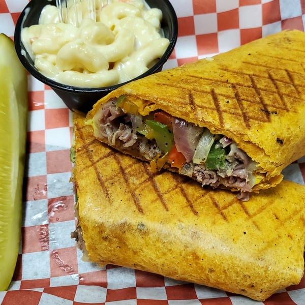 Lake Wales Cheese Shoppe & Deli's grilled wrap with meat, peppers, onions, a side of mac and cheese, and a pickle.