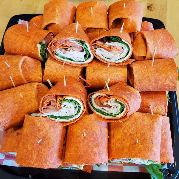 A catering tray filled with Lake Wales Cheese Shoppe & Deli's turkey and tomato wraps.